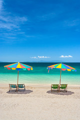 Fototapeta na wymiar Colorful beach chairs with umbrellas on a sunny day.