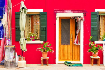 Fototapeta premium Red house with flowers and plants. Colorful house in Burano island near Venice, Italy