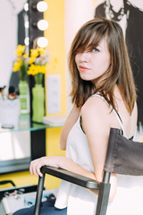 Stylish young woman sitting near makeup mirror with bulb lights. Woman in a beauty salon. Beautiful face with natural makeup