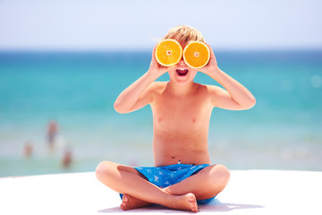 happy, excited kid, boy having fun on the beach, showing orange eyes at summer vacation