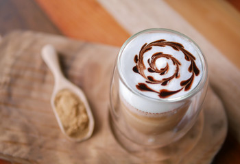 Hot mocha coffee latte art chocolate heart shape spiral glass on table background, vintage style