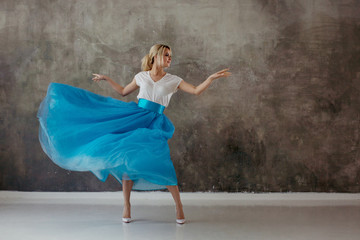 Fototapeta na wymiar Beautiful young woman in a lush blue skirt, whirling and dancing.