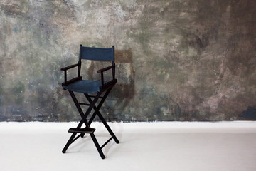 Black Director's chair on grey background. High folding chair on the textured background of the wall