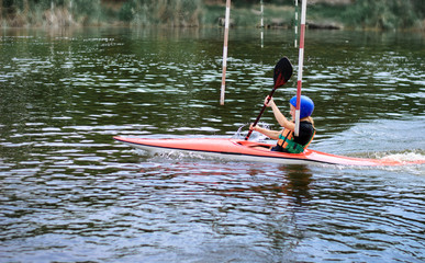 young teenager girl actively manages a sports kayak boat on a beautiful river
