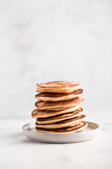 Minimal stack of homemade pancakes on light concrete background, copy space