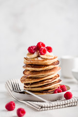 Stack of homemade pancakes with fresh raspberries on light concrete background, close up