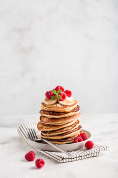Stack of homemade pancakes with fresh raspberries on light concrete background, copy space