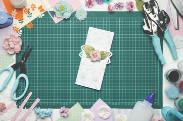 Multi-colored paper card on the cutting mat, tools and materials for scrapbooking, top view