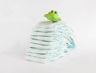 Baby diapers on a white background and a children's toy frog