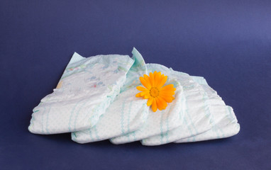 Baby diapers on a blue background and an orange flower on diapers