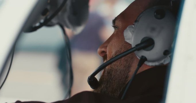 CU Young middle eastern man sits inside a helicopter cockpit wearing headset, preparing for a flight