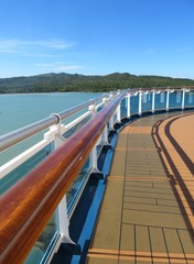 Cruise ship deck and railing with tropical island views in the background
