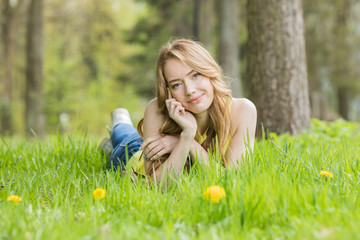 Fototapeta premium Woman lying on dandelions field