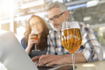 Couple in bar connected on laptop computer, having a drink