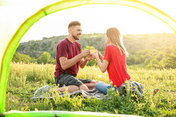 Lovely couple spending time together in wilderness, view from inside of camping tent