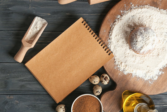 Notebook and ingredients for homemade bread on wooden table