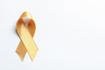 Gold ribbon on white background, top view. Cancer awareness