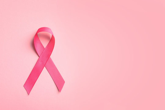 Pink ribbon on color background, top view. Cancer awareness