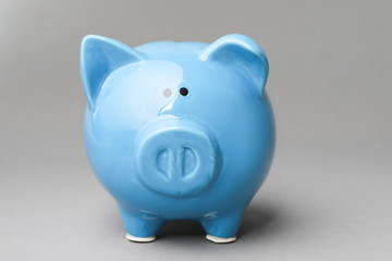 Cute blue piggy bank on gray background