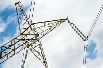 High voltage powerlines and pylon against cloudy sky