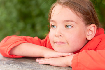  A little girl is sitting in the park at the table.