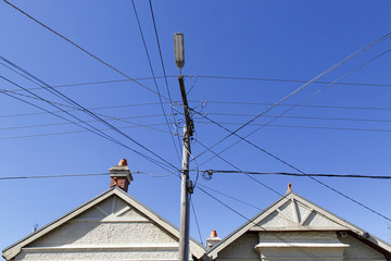 A row of detached houses in a St Kilda suburb. A telegraph pole has many crossing over cables...