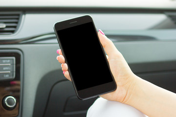 Business girl sitting in car holding a smartphone in her hand, close-up