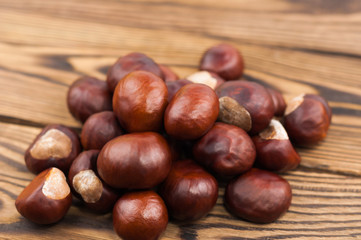 Heap of brown chestnuts on old wooden rustic brown table