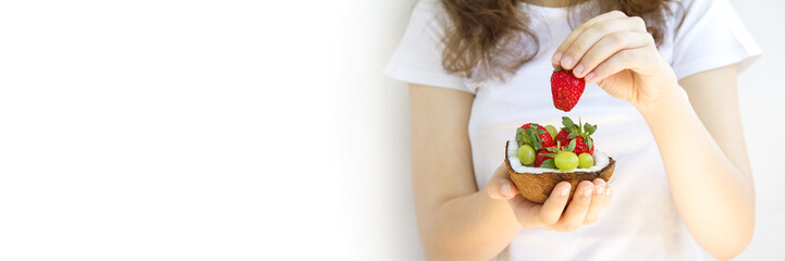 hands holding a dessert of coconut and fruit.