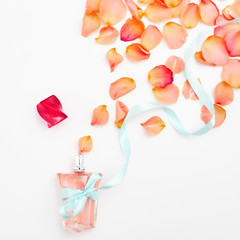 Flat lay. Top view. Minimalist fashion and beauty photo. Delicate roses and perfume bottle on a white background