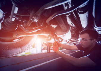 Car mechanic repair car suspension of lifted automobile at repair service station