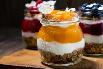 breakfasts in jars with muesli, berry puree and cream, closeup