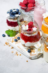 desserts with muesli, berries and fruit in jars, vertical top view
