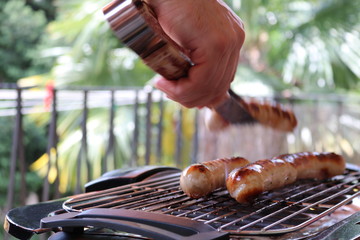 Cooking sausage meat on grill during summer on a balcony 