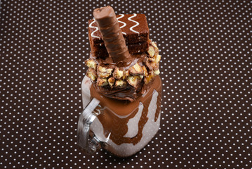 Chocolate extreme milkshake with brownie cake, chocolate paste and sweets. Crazy freakshake food trend. Copy space