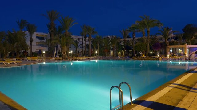 Timelapse evening light under water swimming pool and palm trees on background