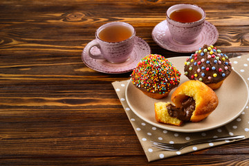 Baking with tea and chocolate on the table.  Two cups of tea with cupcakes and chocolate with a multicolored powder on the table.