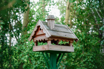Wooden bird feeder in the background of trees in summer