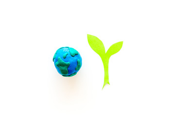 Planet, ecology. plastiline symbol of planet Earth globe and plant coutout on white background top view copy space