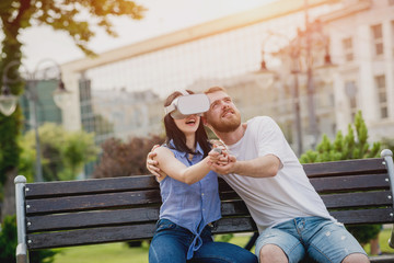 A young couple plays a game using virtual reality glasses on the street.