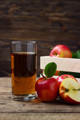 Glass of apple juice with red apples on wooden table