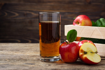 Glass of apple juice with red apples on wooden table