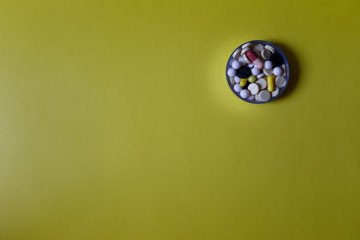 Assorted pharmaceutical medicine pills, tablets and capsules on yellow background. Copy space for text