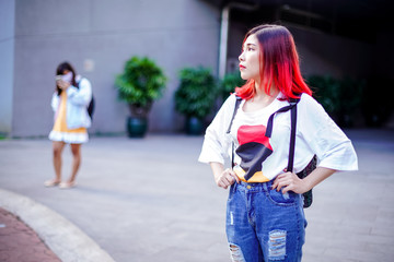 Young girl student with red hair is waiting for bus in university. Fashion and life style.