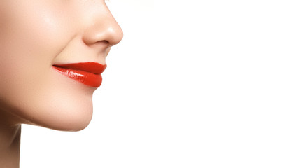 Naklejka premium Cosmetics, makeup and trends. Bright lip gloss and lipstick on lips. Closeup of beautiful female mouth with red lip makeup. Beautiful part of female face. Perfect clean skin in red light