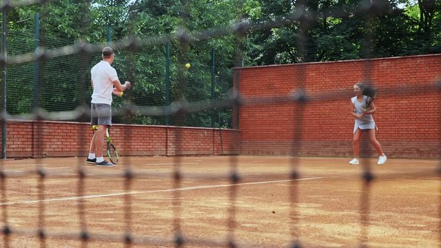 Coacher teaching young girl to playing tennis.