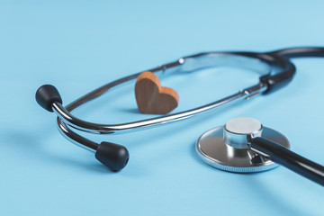 Stethoscope and wooden heart on blue background close-up