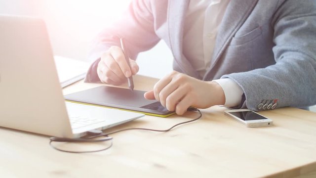 Young man designer in glasses works on a graphic tablet