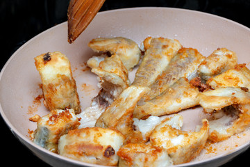 Pieces of fish fried in a hot pan