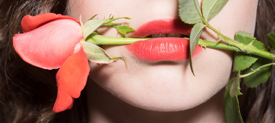 Passion. Mouth of young girl with red rose between lips. Female desire, beautiful red flower....